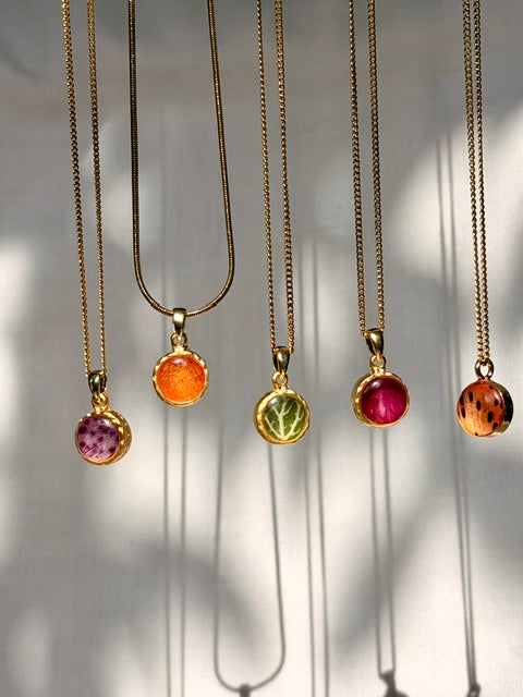 vijf kleine botanische hangers met elk een ander bloemblad en verschillende patronen in kleuren paars, oranje, groen, roze
