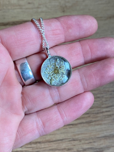 Verzilverde elegante hanger met detail van witte schermbloem.