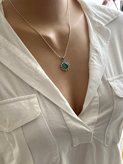 Silver plated flower pendant with green leaf detail.