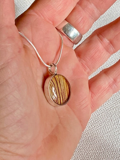 Zilveren hanger met gestreept detail van de trompetbloem.