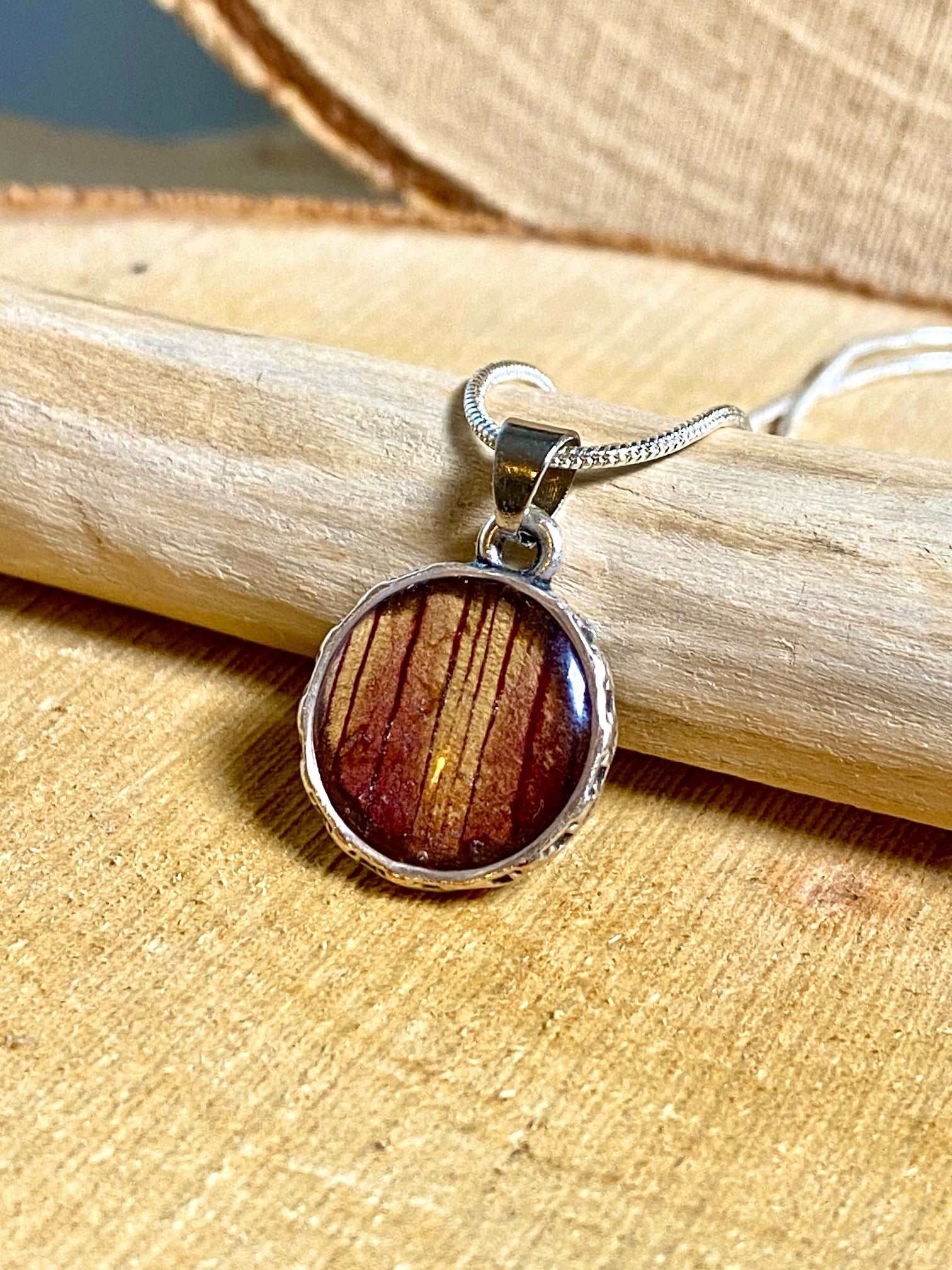 Verzilverde ronde hanger met rood-gele Trompetbloem.