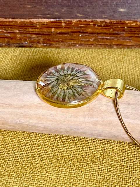 goudkleurige ronde hanger met een echte bloem van de klaver