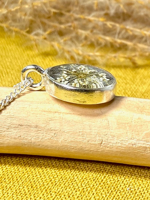 Verzilverde elegante hanger met detail van witte schermbloem.