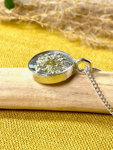 Verzilverde elegante hanger met detail van witte schermbloem.