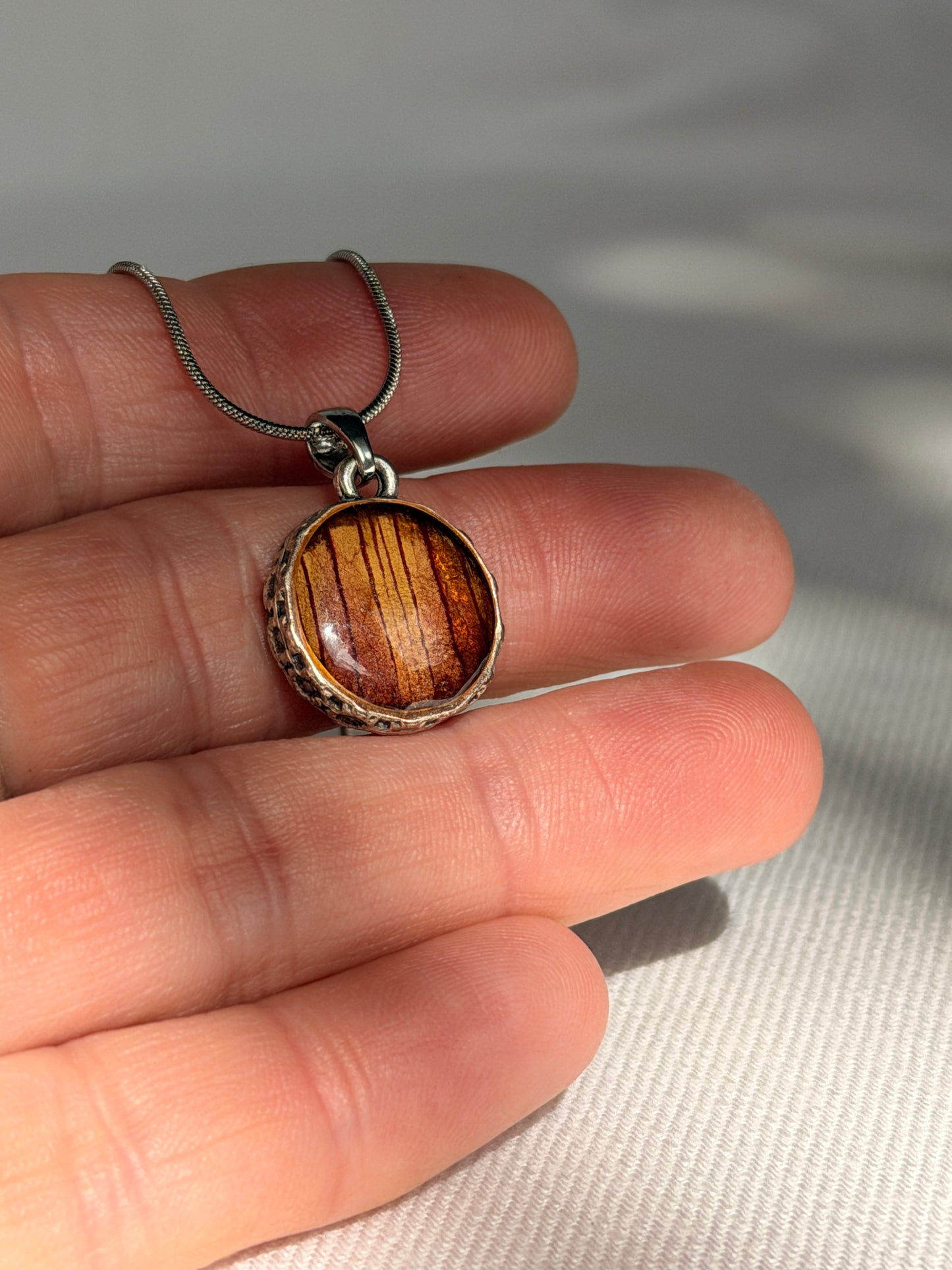 Verzilverde ronde hanger met rood-gele Trompetbloem.