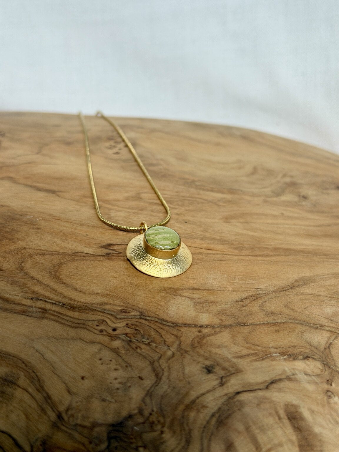 Vergulde varenbladhanger met 18k vergulde snakeketting op hout