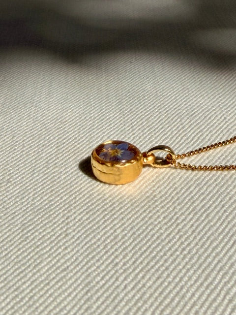 Fijne gouden ketting met kleine hanger en blauw bloemdetail