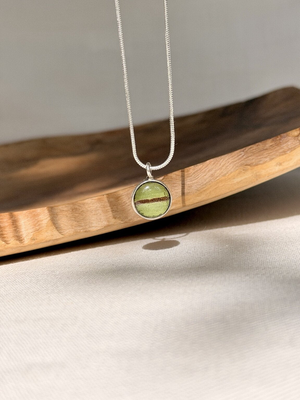 Kleine verzilverde hanger met varenblad gedragen aan een 925 zilveren snake ketting