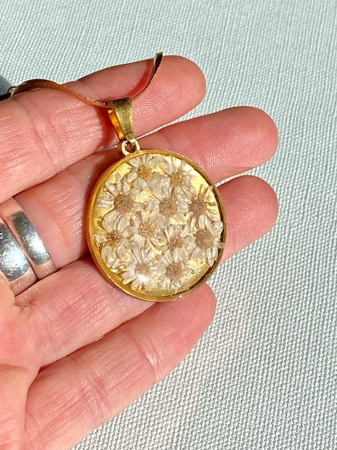 Madeliefjes in een grote ronde hanger, goldplated.