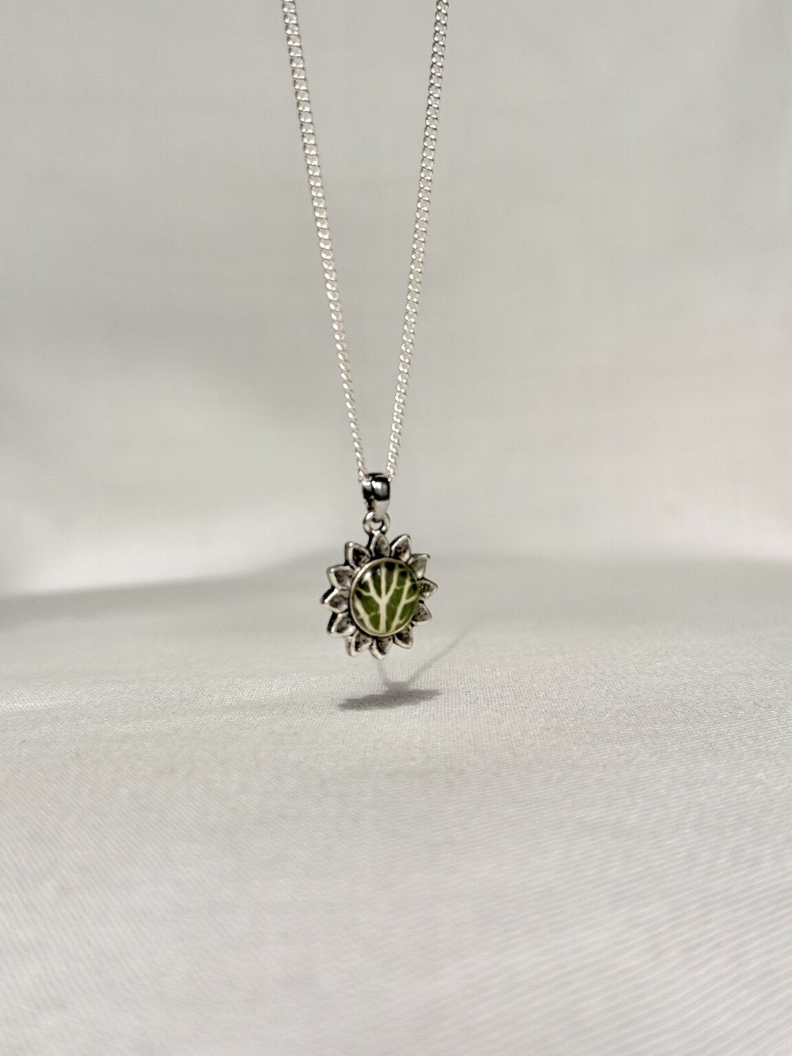Bloemvormige hanger met groen Fittonia-blad aan een zilveren snake ketting