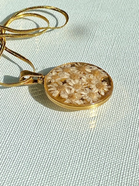 Madeliefjes in een grote ronde hanger, goldplated.