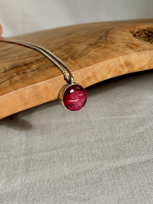 Detail van de rode rozenbladhanger met verzilverde rand en zilveren ketting