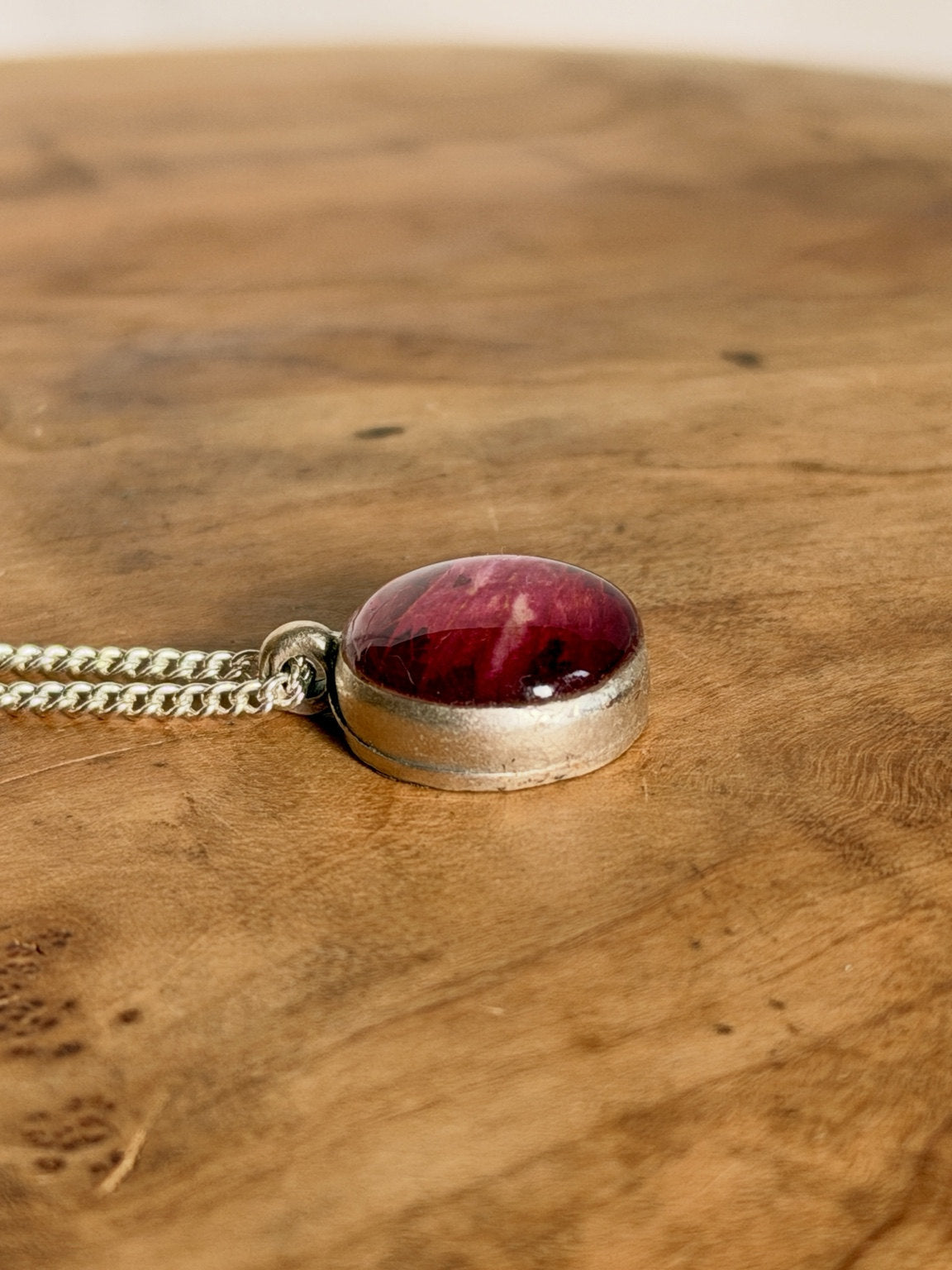 Ronde hanger met dieprood rozenblad op een houten ondergrond