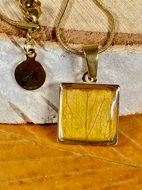 Petit pendentif carré doré avec feuille de hêtre jaune doré.